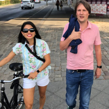 Frau mit Fahrrad und ein Mann laufen gemeinsam auf einem Gehweg