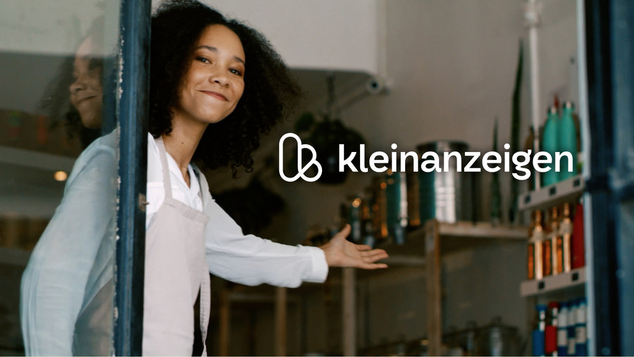 The new Kleinanzeigen logo, presented by a smiling sales assistant welcoming visitors to her shop.