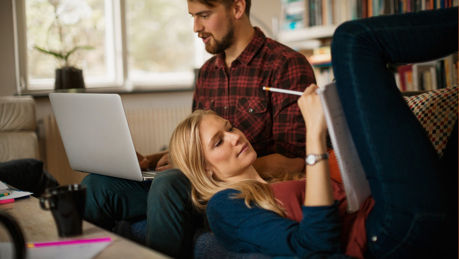 A young couple working together on the couch.