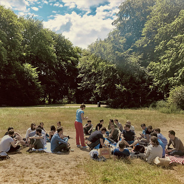 Mehrere Personen sitzen auf einer grünen Wiese im Park